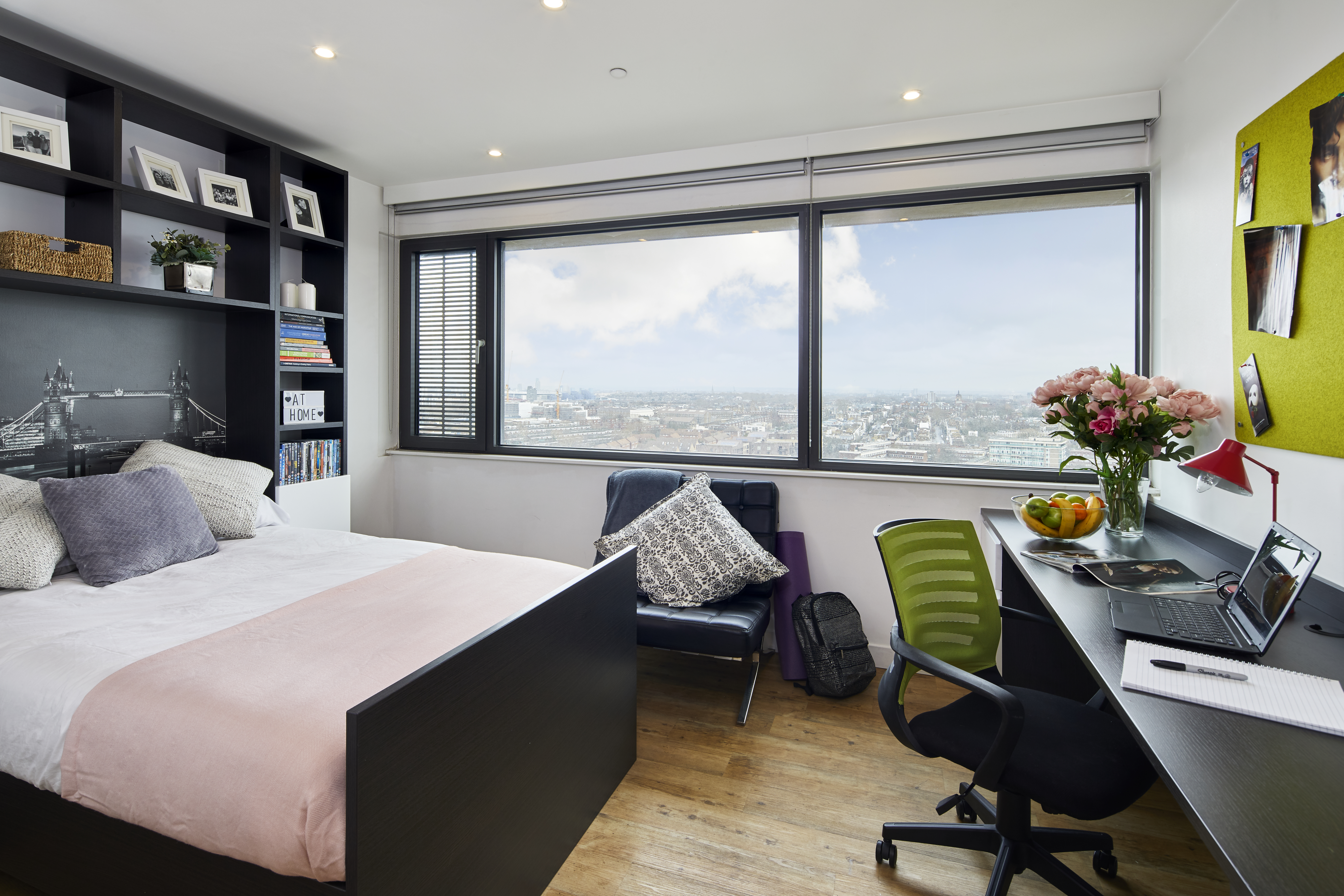 Bright furnished student bedroom with desk, bed and city view